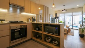 A modern kitchen with built-in appliances, wooden shelves, and pendant lighting.