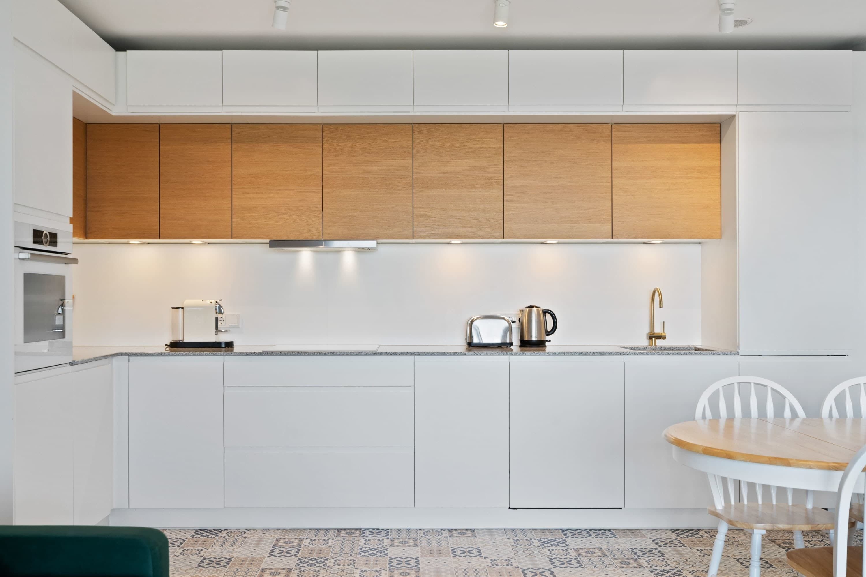 A modern kitchen with white cabinetry, a wooden countertop, and a small dining area with a table and chairs.