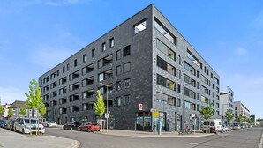 A modern multi-story building with a dark facade, large windows, and a visible storefront.