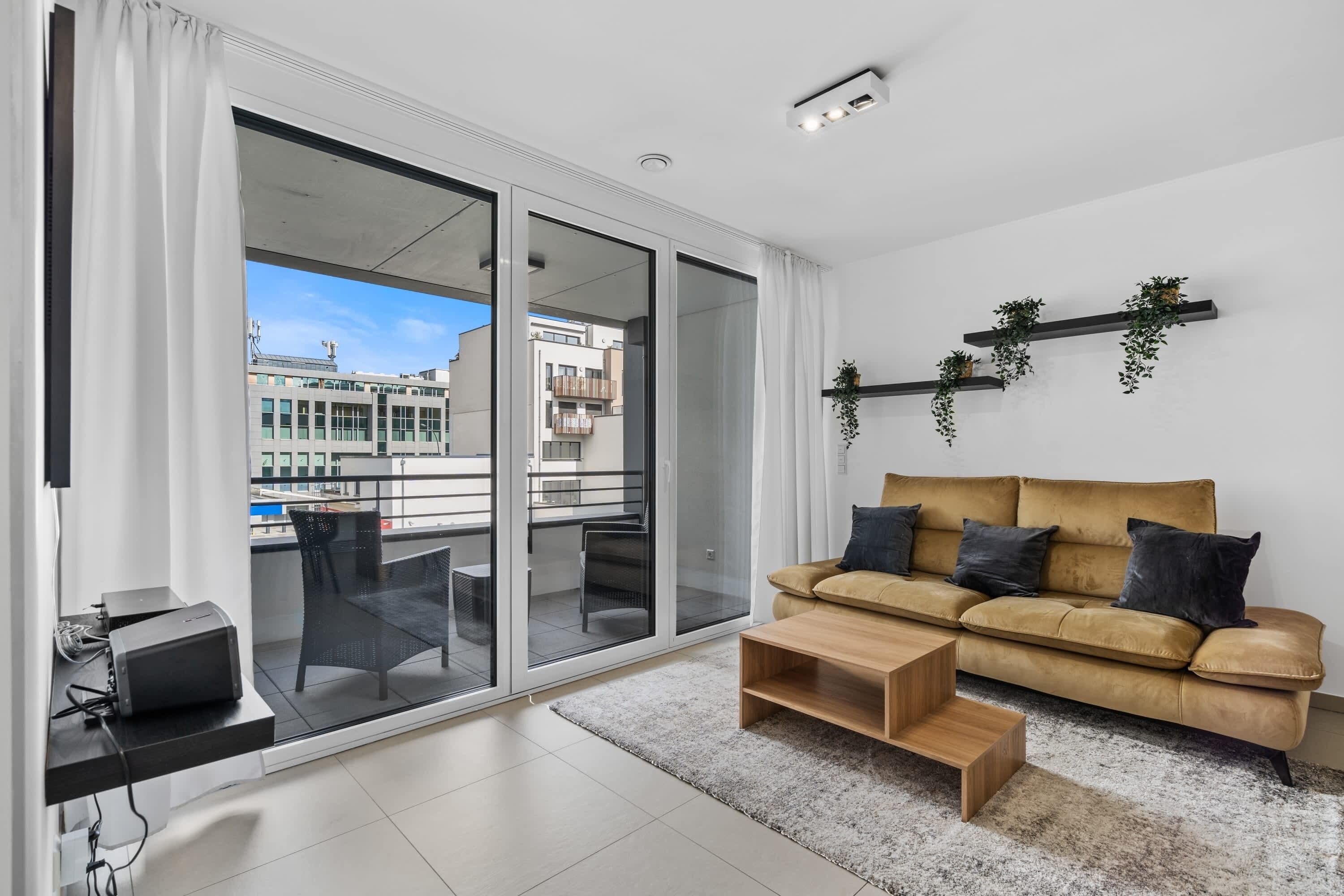 Enjoy a bright and airy living room with direct access to a private balcony, perfect for relaxing with a cup of coffee or a good book. The space is complemented by a comfortable sofa and modern decor.