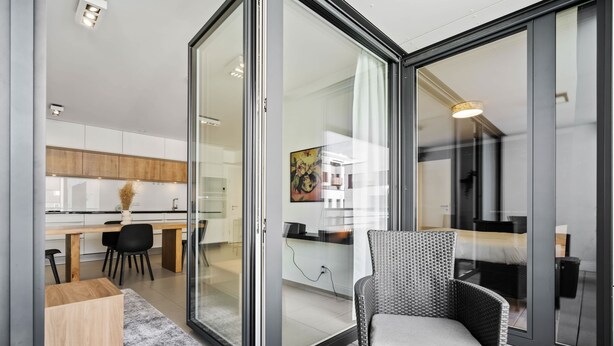 A modern kitchen with white cabinets, a dining table, and black chairs.