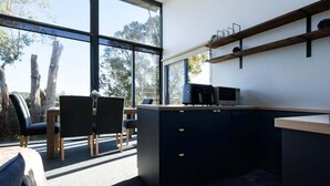 Une cuisine moderne avec une grande fenêtre, un coin repas avec des chaises, et un animal de compagnie visible.