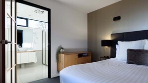 Une chambre d’hôtel comprenant un lit, un bureau, une chaise, une table de chevet et une lampe.