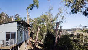 Un bâtiment à la structure métallique, doté d’un balcon, entouré d’arbres et surplombant un ciel dégagé.