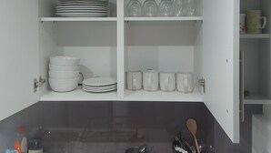 Cocina con alacenas abiertas que contienen platos, tazones, copas de vino y tazas.