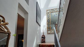 Una scala con un tappeto decorato, un lampadario e uno specchio incorniciato.