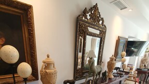 Un pasillo ricamente decorado con suelo de mármol, muebles ornamentales y diversos objetos decorativos como jarrones y esculturas.