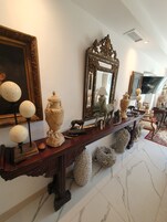 Un pasillo ricamente decorado con suelo de mármol, muebles ornamentales y diversos objetos decorativos como jarrones y esculturas.