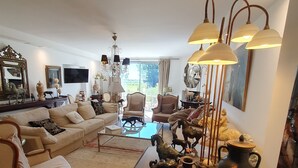 Un salón amplio con un sofá grande, sillones, una mesita de centro y un jarrón decorativo.
