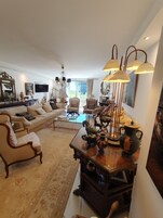 Uma sala de estar espaçosa com um sofá grande, poltronas, uma mesa de centro e um vaso decorativo.