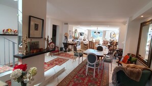 Un amplio salón con un tapete rojo estampado, una mesa de comedor con sillas y un sofá verde.