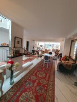 Uma sala de estar ampla com um tapete vermelho estampado, uma mesa de jantar com cadeiras e um sofá verde.