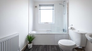Ein kleines Badezimmer mit Dusche, Toilette und einem kleinen Fenster.