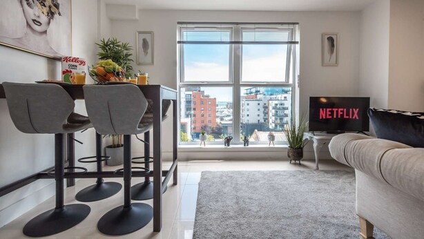 Un soggiorno moderno con zona pranzo, un'ampia finestra vista città, una TV a schermo piatto e un divano accogliente.