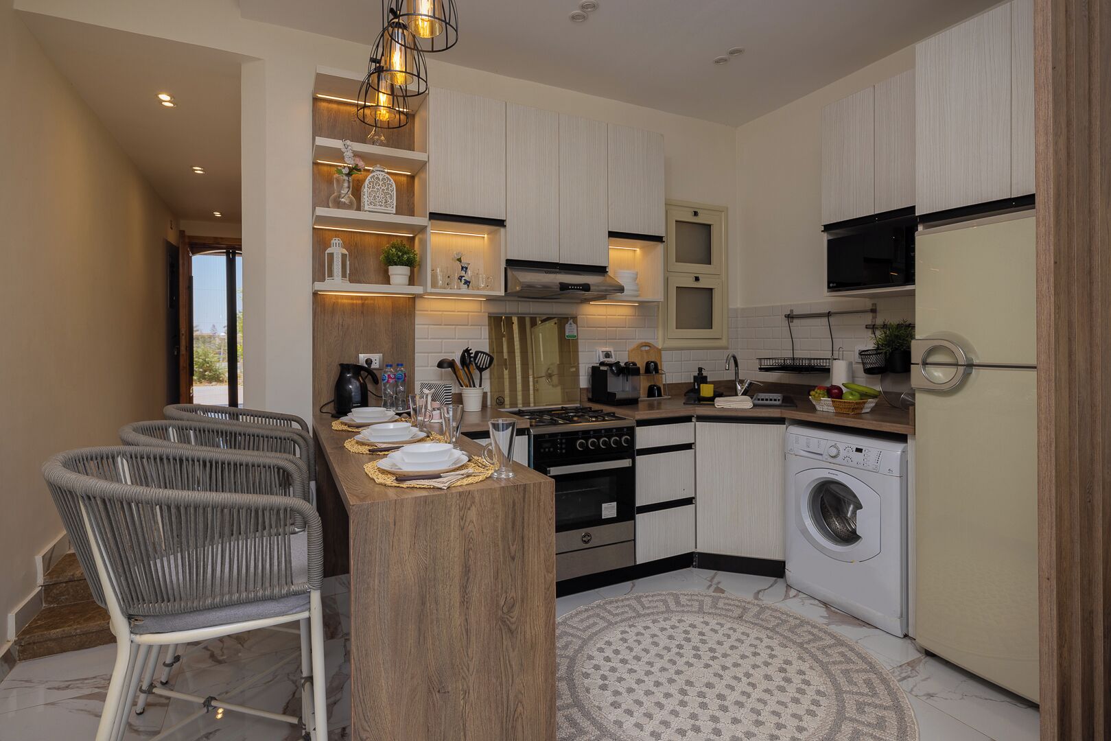 A modern kitchen with a central island, built-in appliances, and a dining area with a bar stool.