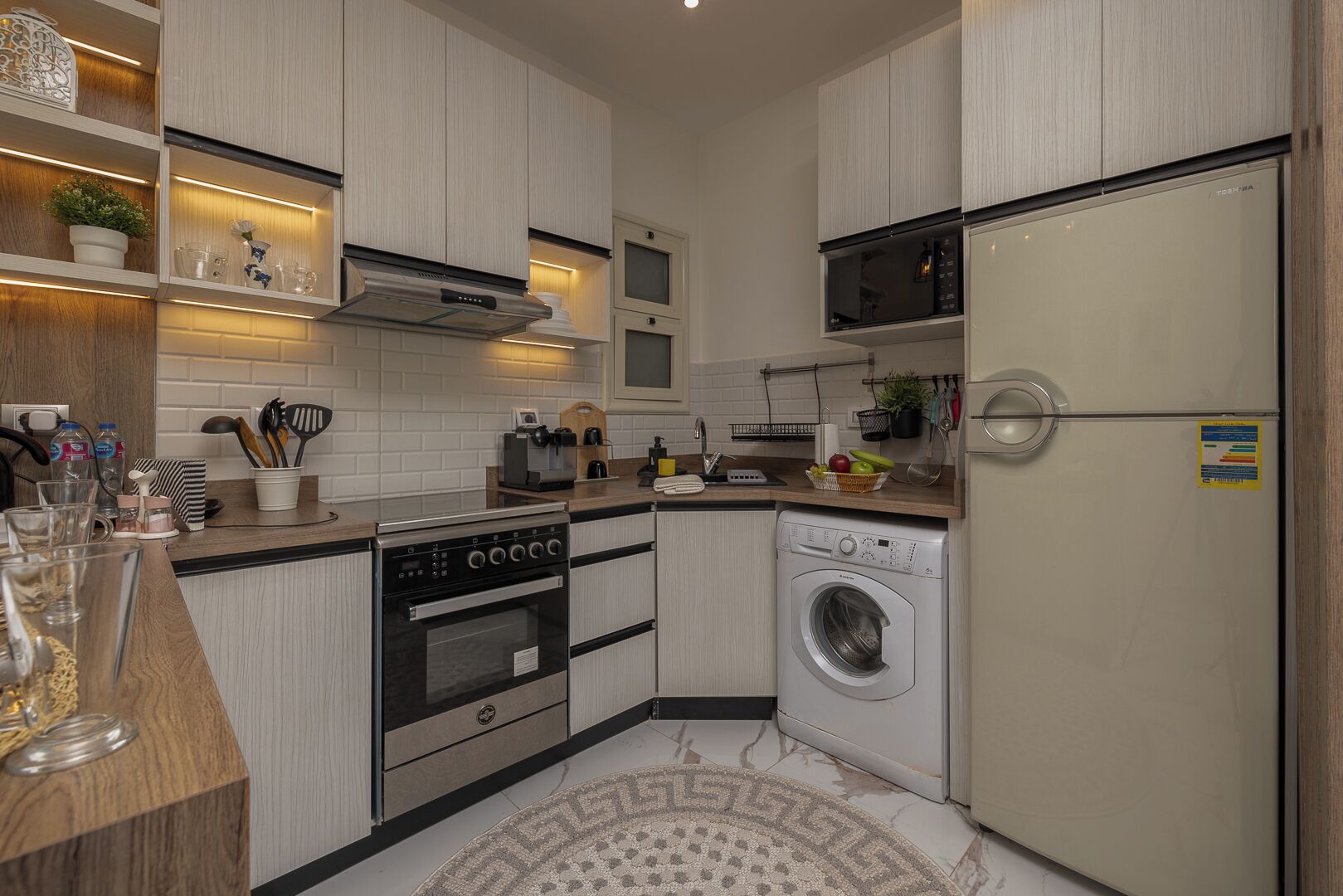 A compact kitchen with a built-in oven, microwave, and washing machine.