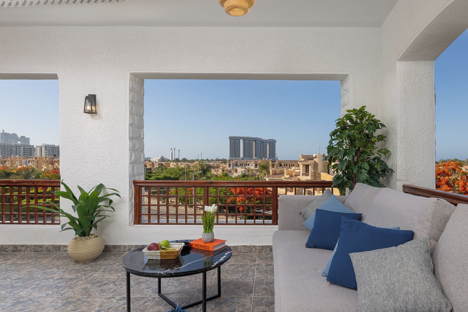 Een balkon met een bank, een tafel en een potplant.