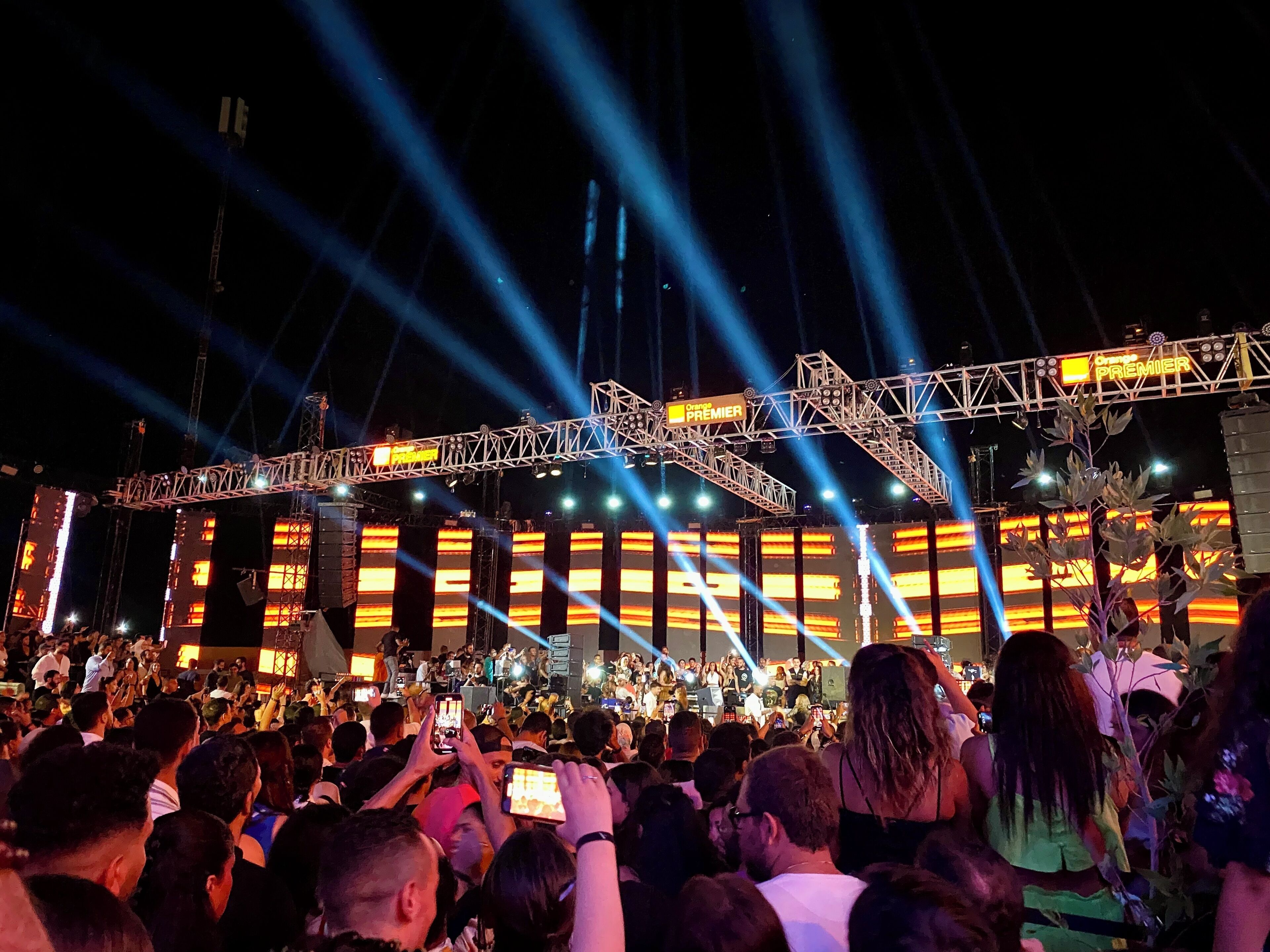 A crowded outdoor event with a stage and a large audience.