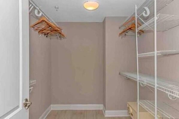 A closet with wooden hangers and white shelving units. - Luxury 4BR Oceanfront • North Beach Towers (North Myrtle Beach)