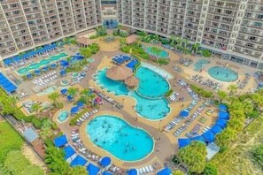 A hotel with multiple swimming pools, sun loungers, and a central fountain. - Luxury 4BR Oceanfront • North Beach Towers (North Myrtle Beach)