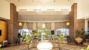 A spacious lobby with high ceilings, large windows, and multiple potted plants. - Carmel Seaside Sunny Stays by Sea N Rent (Haifa)