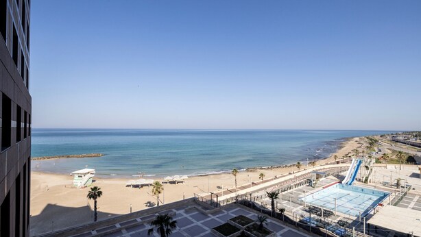 A beach view with a pool and a lifeguard tower. - Carmel Seaside Sunny Stays by Sea N Rent (Haifa)