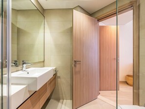 A modern bathroom with a large mirror, a sink, and a wooden door. - Condo With Burj Khalifa View In City (Dubai)