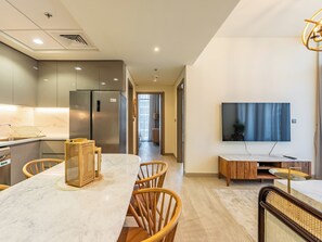 A modern kitchen with a marble countertop, stainless steel appliances, and wooden chairs.