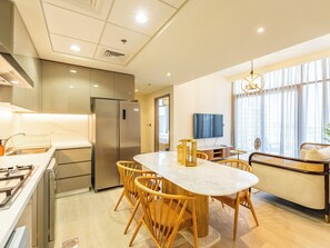 A modern kitchen with a built-in refrigerator, a dining table with wooden chairs, and a TV mounted on the wall.