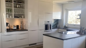 Una cocina moderna con armarios blancos, una isla central y un horno empotrado.