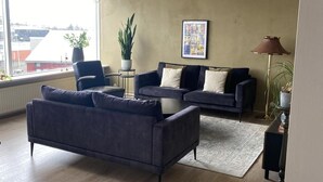Un salón con sofá, dos sillones, una mesita de centro, una lámpara de pie y una planta en maceta.