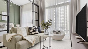 A modern living room with a sofa, a round coffee table, and a television. - Silkhaus Socio Towers Dubai Hills (Dubai)