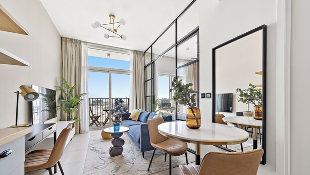 A modern living room with a sofa, chairs, a dining table, and a TV. - Silkhaus Socio Towers Dubai Hills (Dubai)