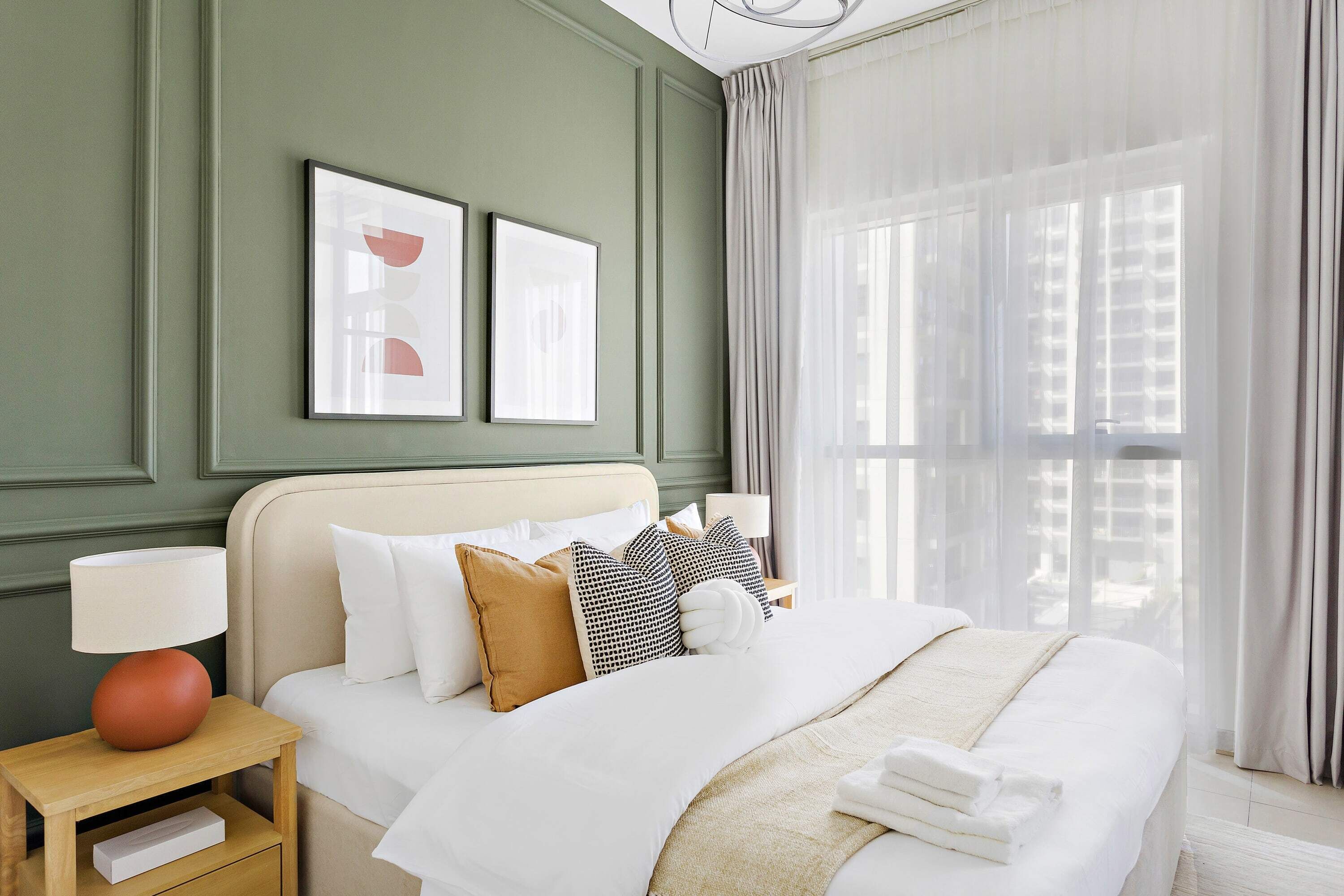 A neatly made bed with white and brown bedding, a bedside lamp, and a nightstand with a drawer.