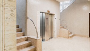 Een modern interieur met een marmeren trap, een lift en een glazen wand.