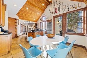 A modern kitchen with wooden cabinets, a central island, and blue chairs around a white table. - Chateau Hadarian (Vail)