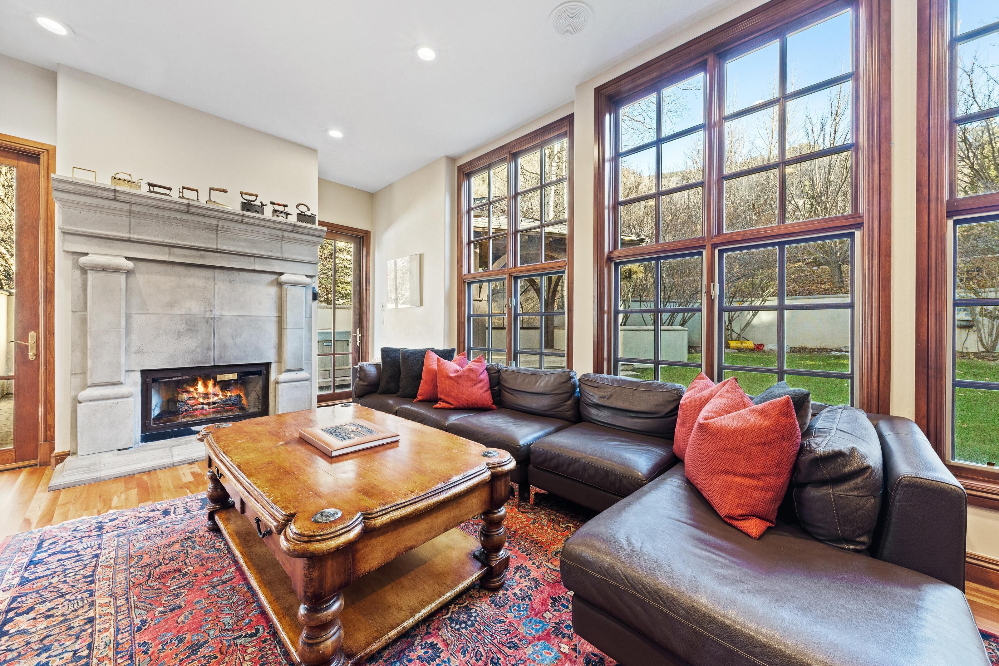 A living room with a fireplace, leather sofa, and large windows.