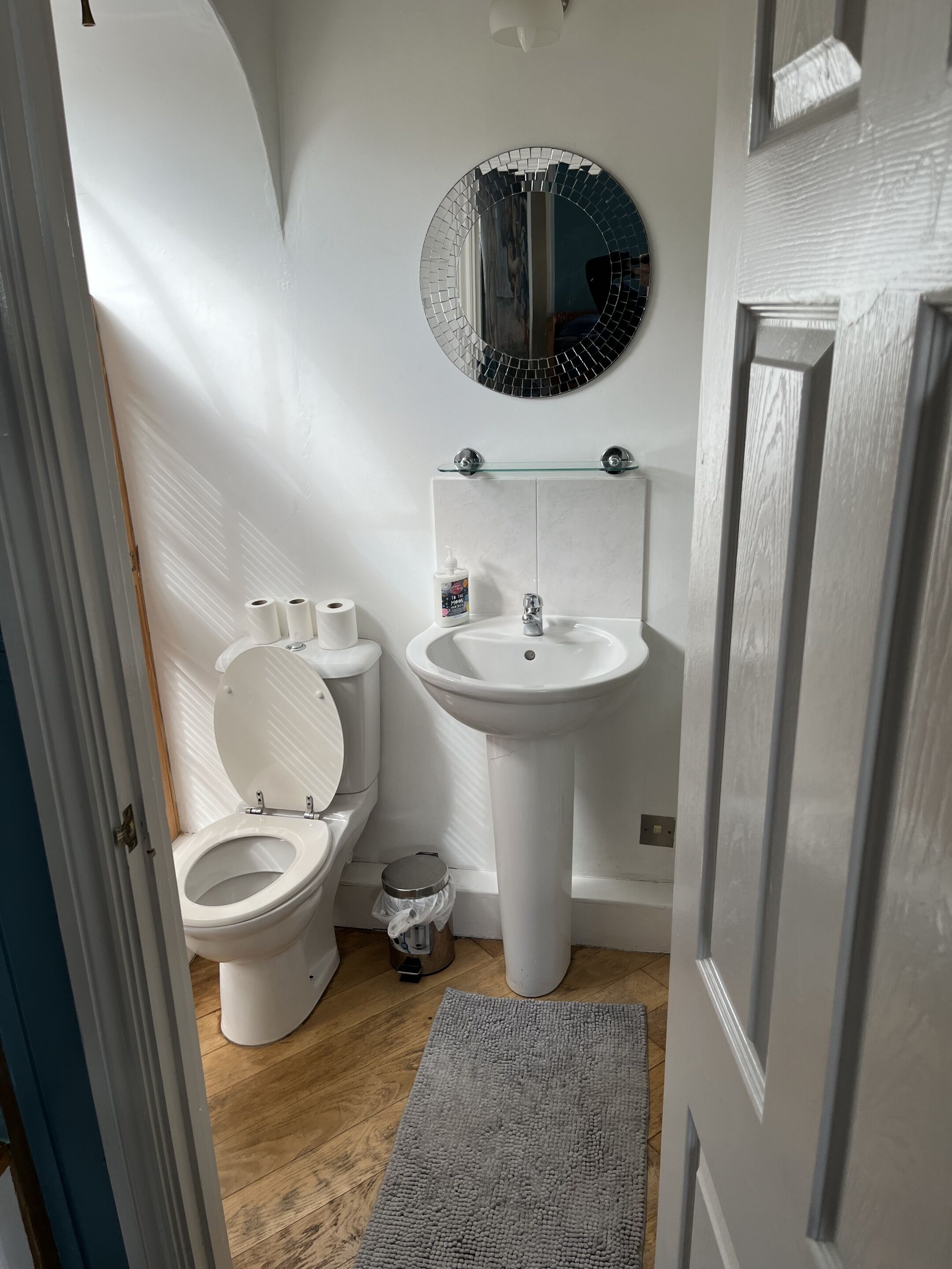 A bathroom with a toilet, sink, and mirror.