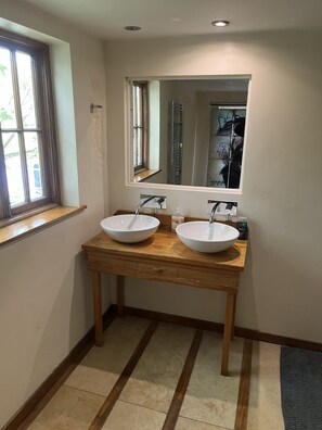 A bathroom with two white sinks, wooden vanity, and a large mirror.