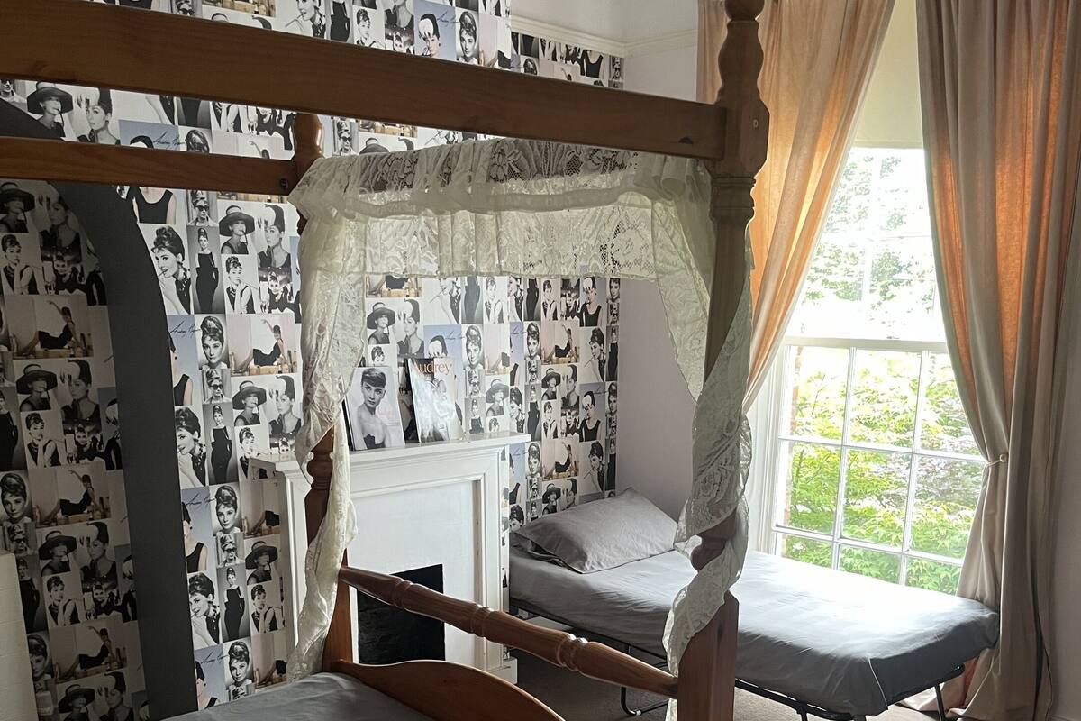 A room with bunk beds, a small desk, and a window with curtains.