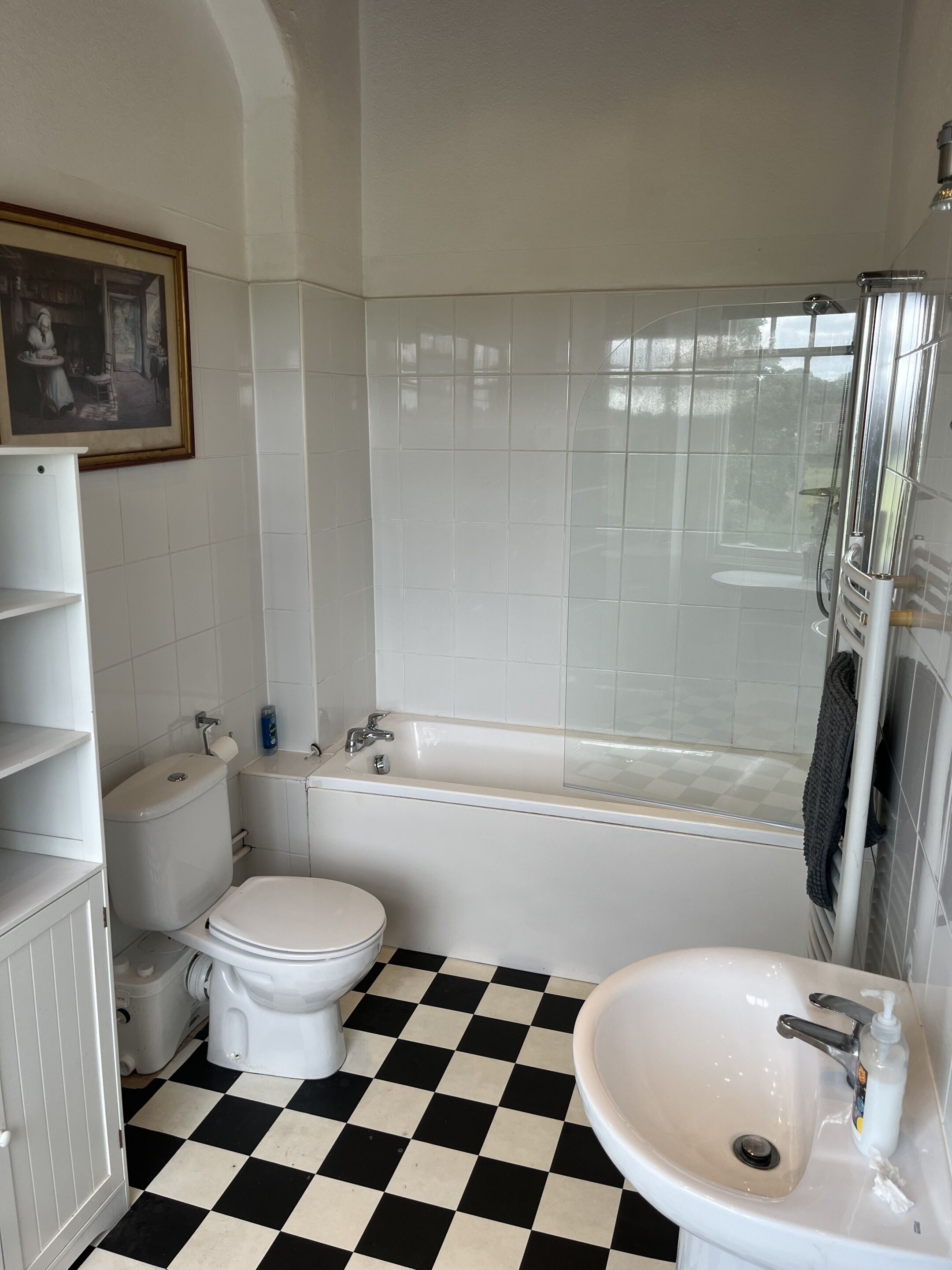 A bathroom with a checkered floor, a bathtub, a toilet, and a sink.