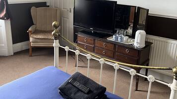 A hotel room with a bed, a television, a chair, a dresser, and a painting on the wall.