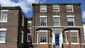 A two-story brick building with a blue door and white-framed windows.