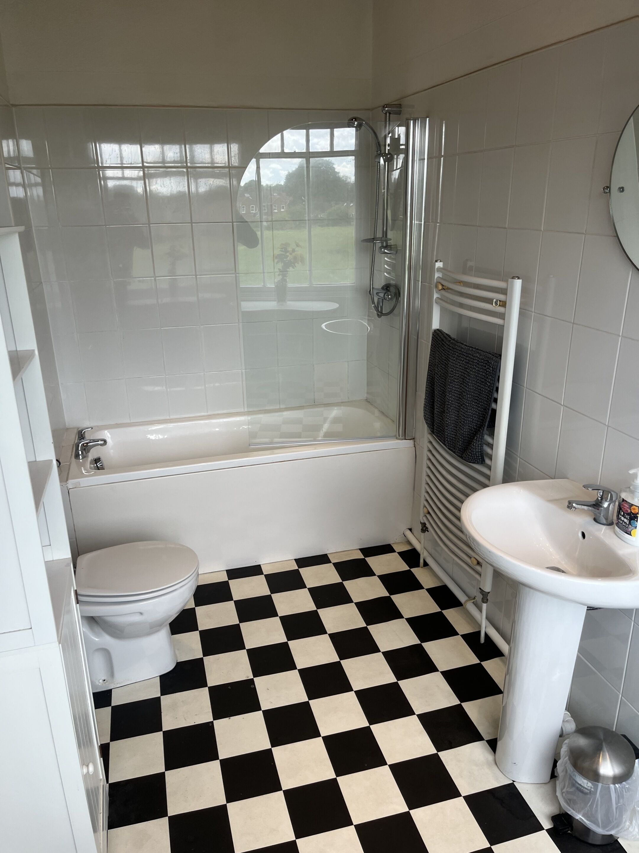 A bathroom with a checkered floor, a bathtub, a toilet, a sink, and a shower.