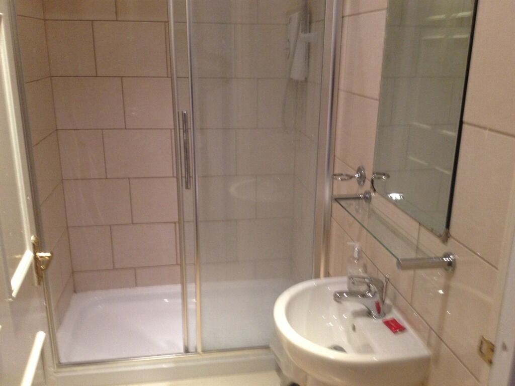 A bathroom with a glass shower enclosure, a white sink, and a mirror above the sink.