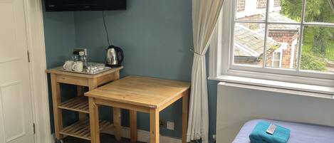 Una habitación con dos camas, un escritorio, un televisor y una ventana con cortinas.