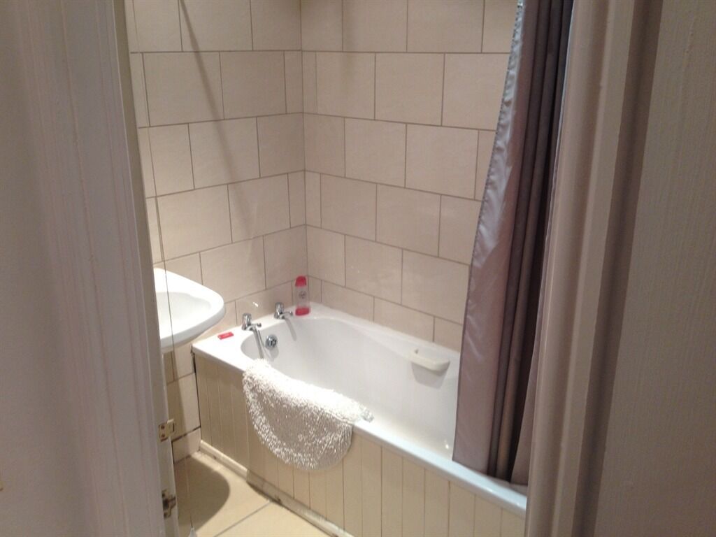 A bathroom with a bathtub, a sink, and a shower curtain.