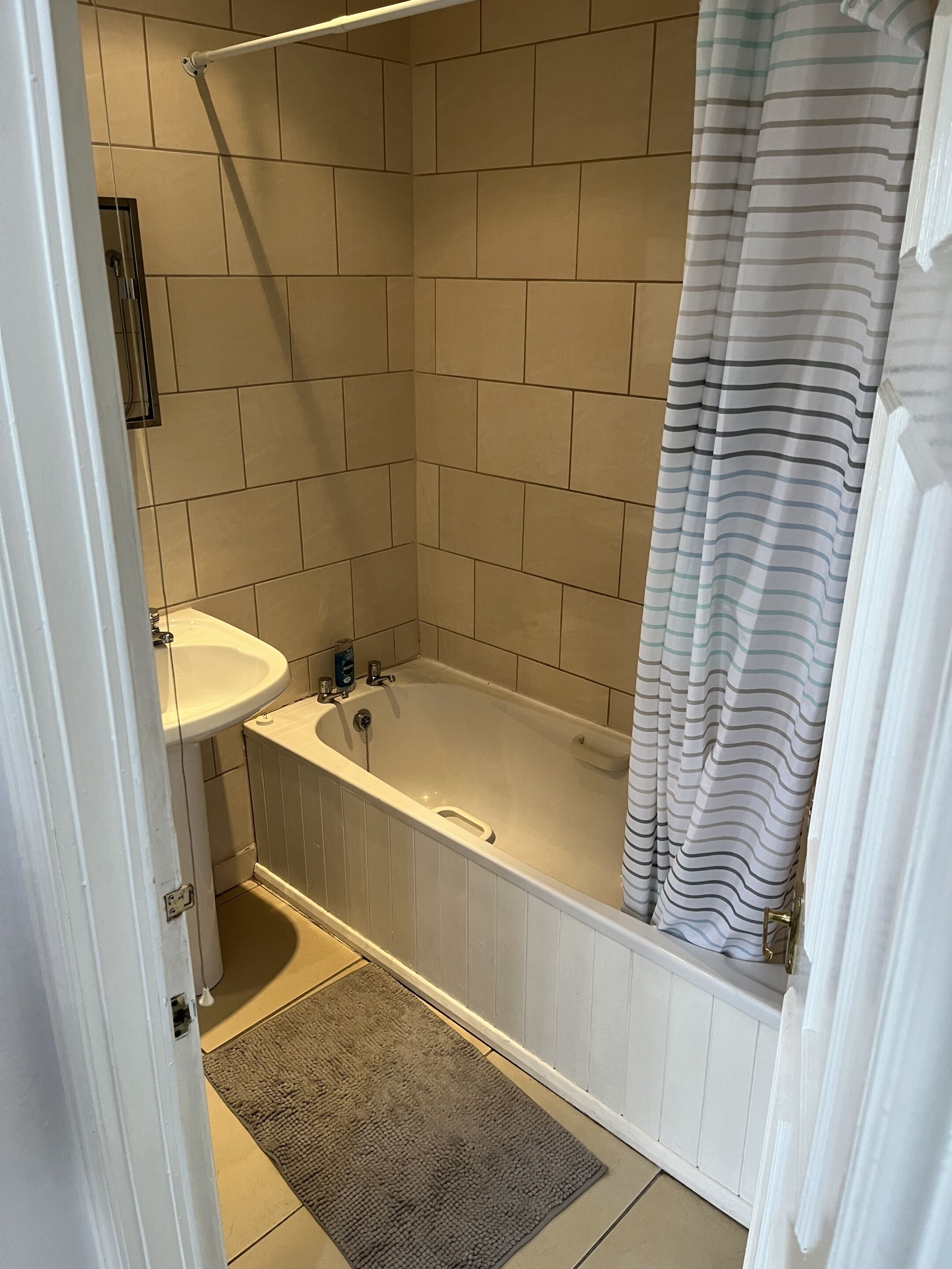 A bathroom with a bathtub, a sink, and a shower curtain.