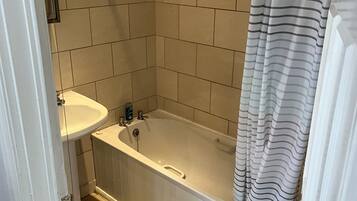 A bathroom with a bathtub, a sink, and a shower curtain.