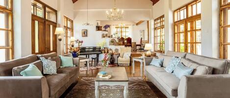 A spacious living room with two sofas, a coffee table, and a piano.